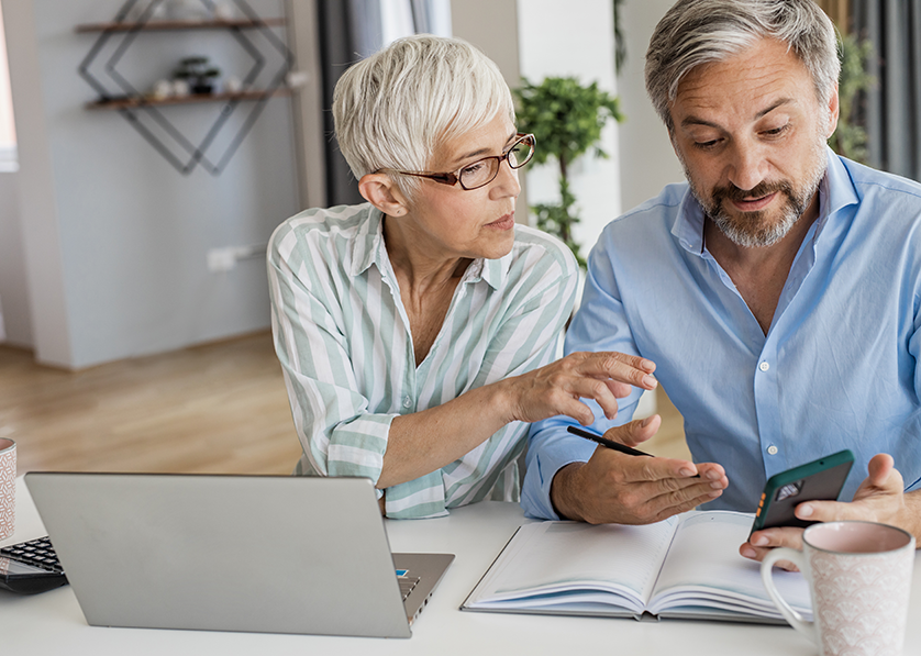 Couple reviewing finances together at home using a laptop and smartphone