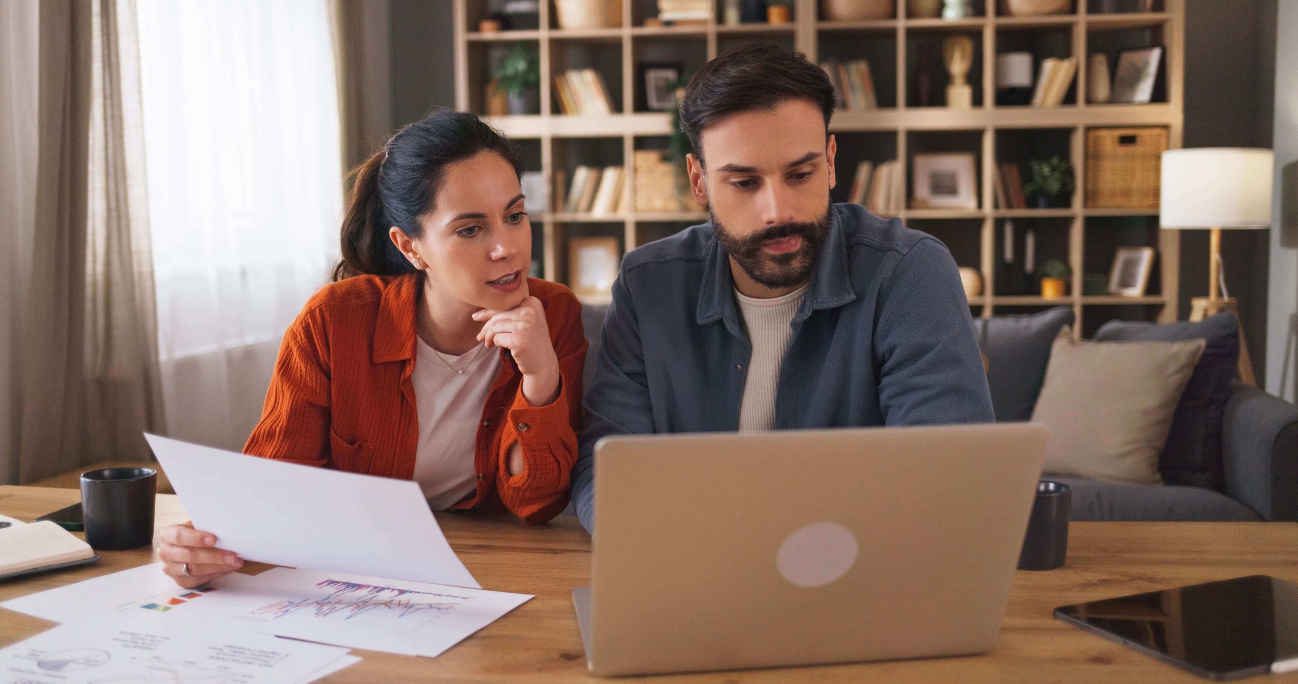 Couple reviewing financial documents and planning their finances together at home