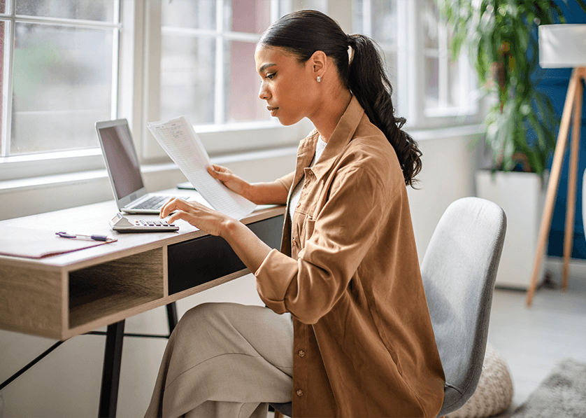 Professional reviewing financial documents and calculating expenses at a desk