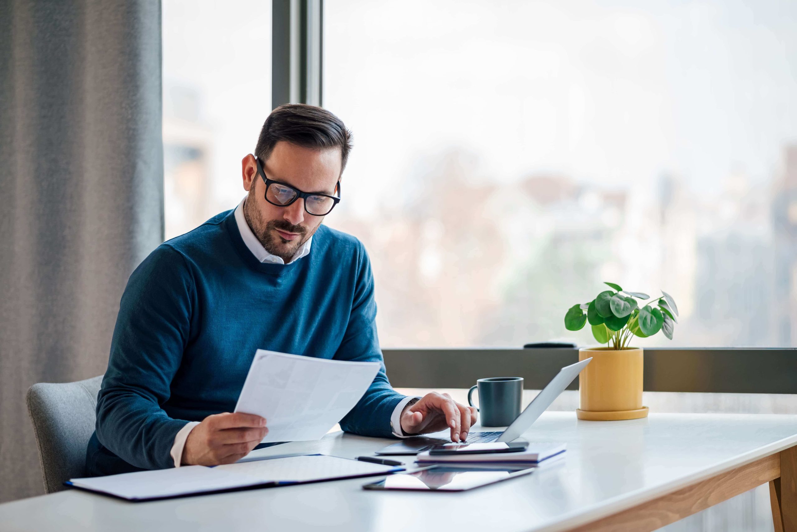 Business owner reviewing financial documents and working on a laptop